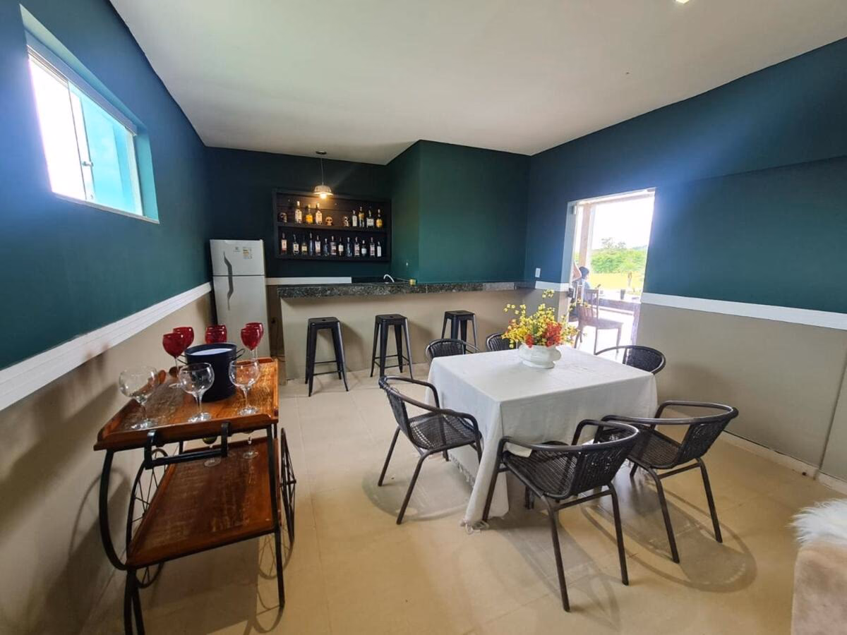 Sala de convívio verde-petróleo com adega e taças de vinho