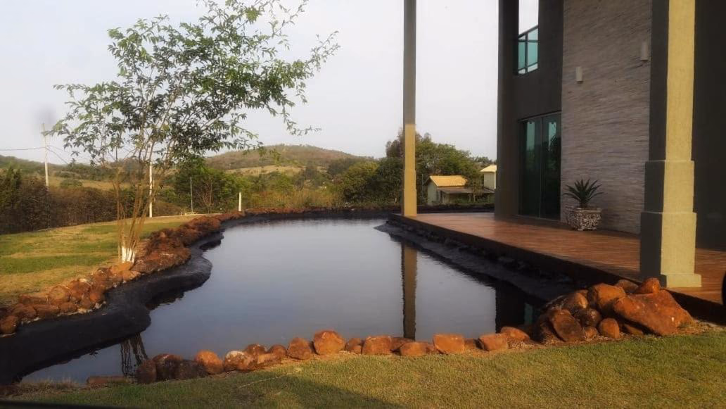 Fachada da casa vista da rua, com muro de vidro e jardim frontal