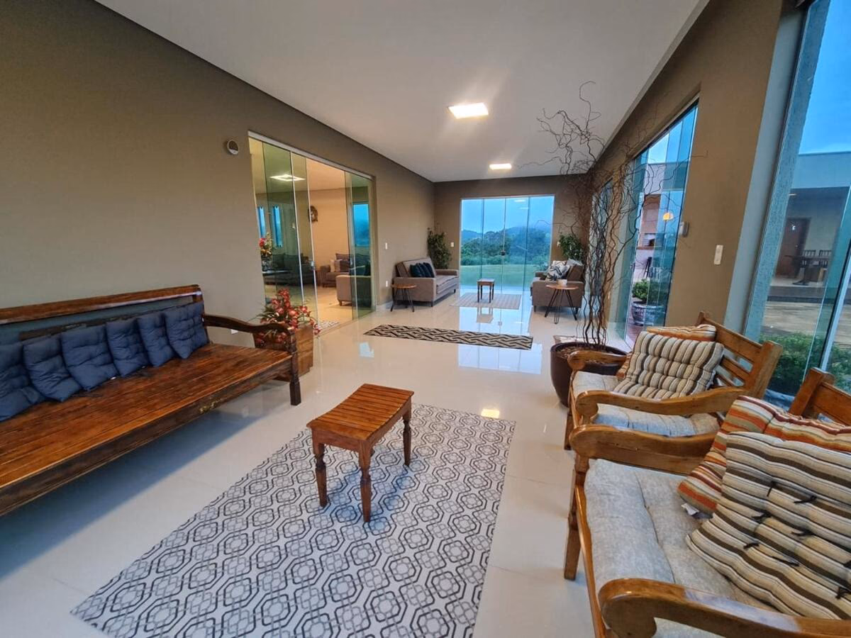 Sala de estar com bancos de madeira e vista panorâmica da serra