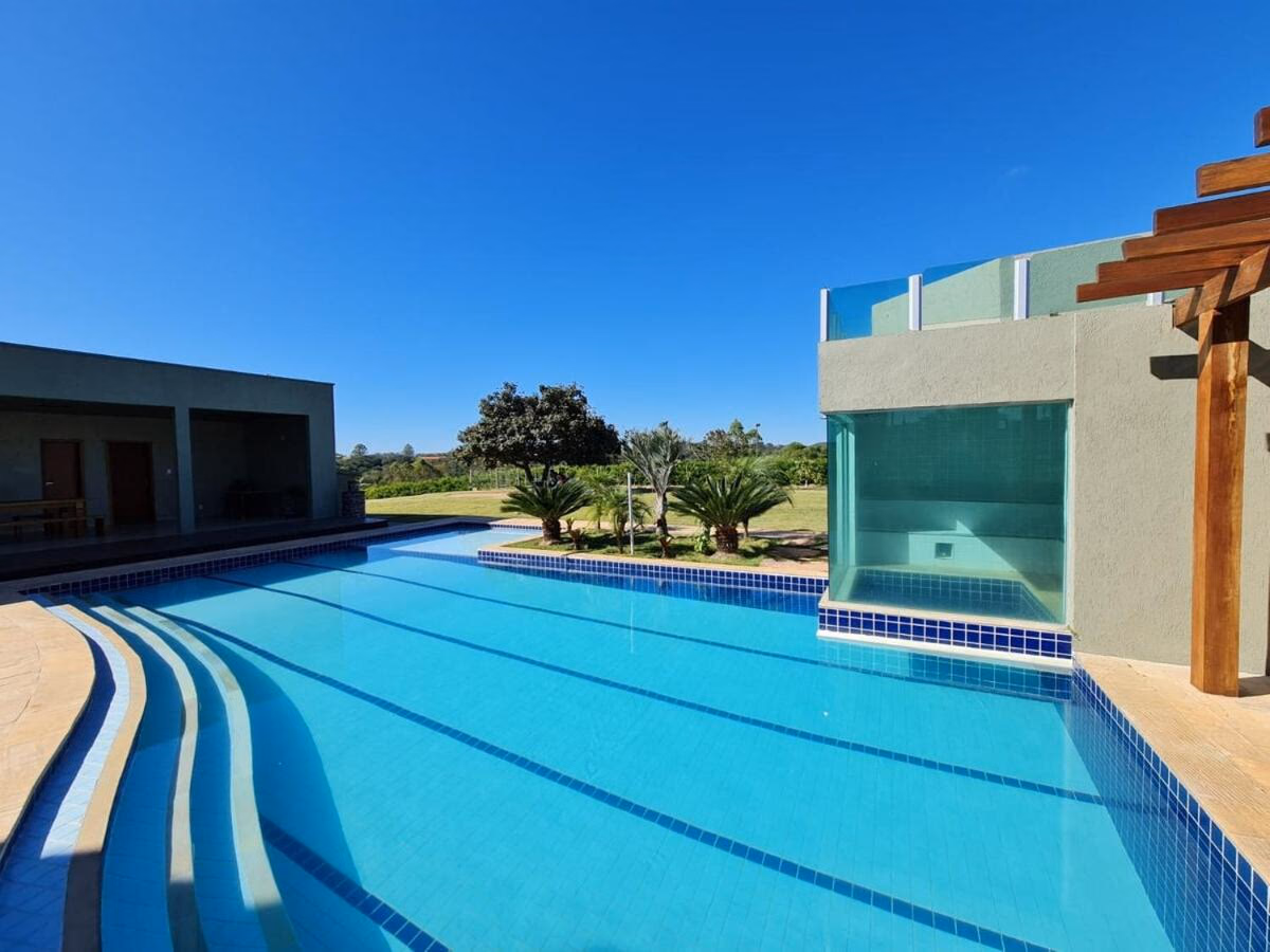 Piscina com raia esportiva e volume envidraçado da sauna ao fundo