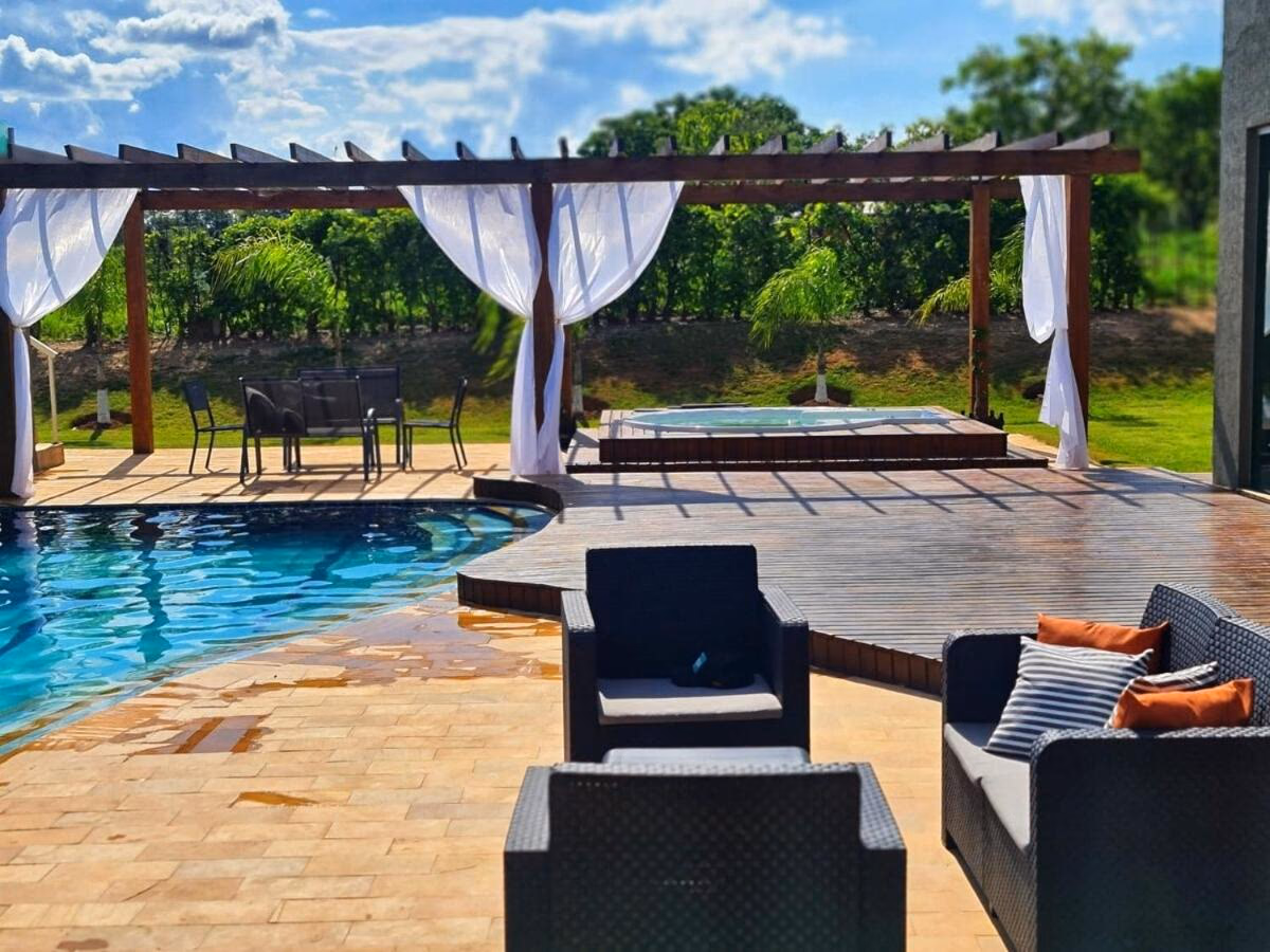 Piscina e hidromassagem sob pergolado de madeira, vistos do primeiro pavimento