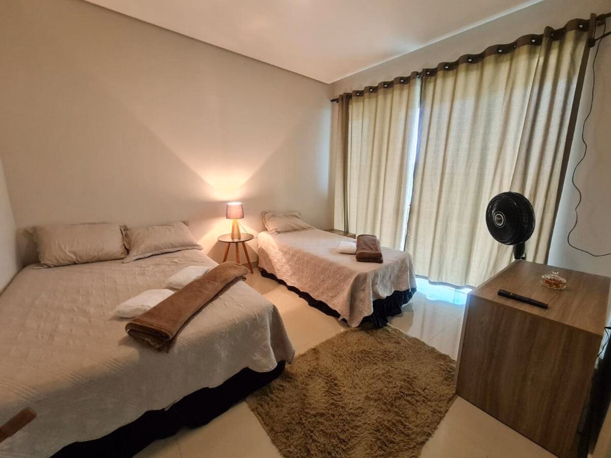 Quarto com duas camas de casal e cortinas bege