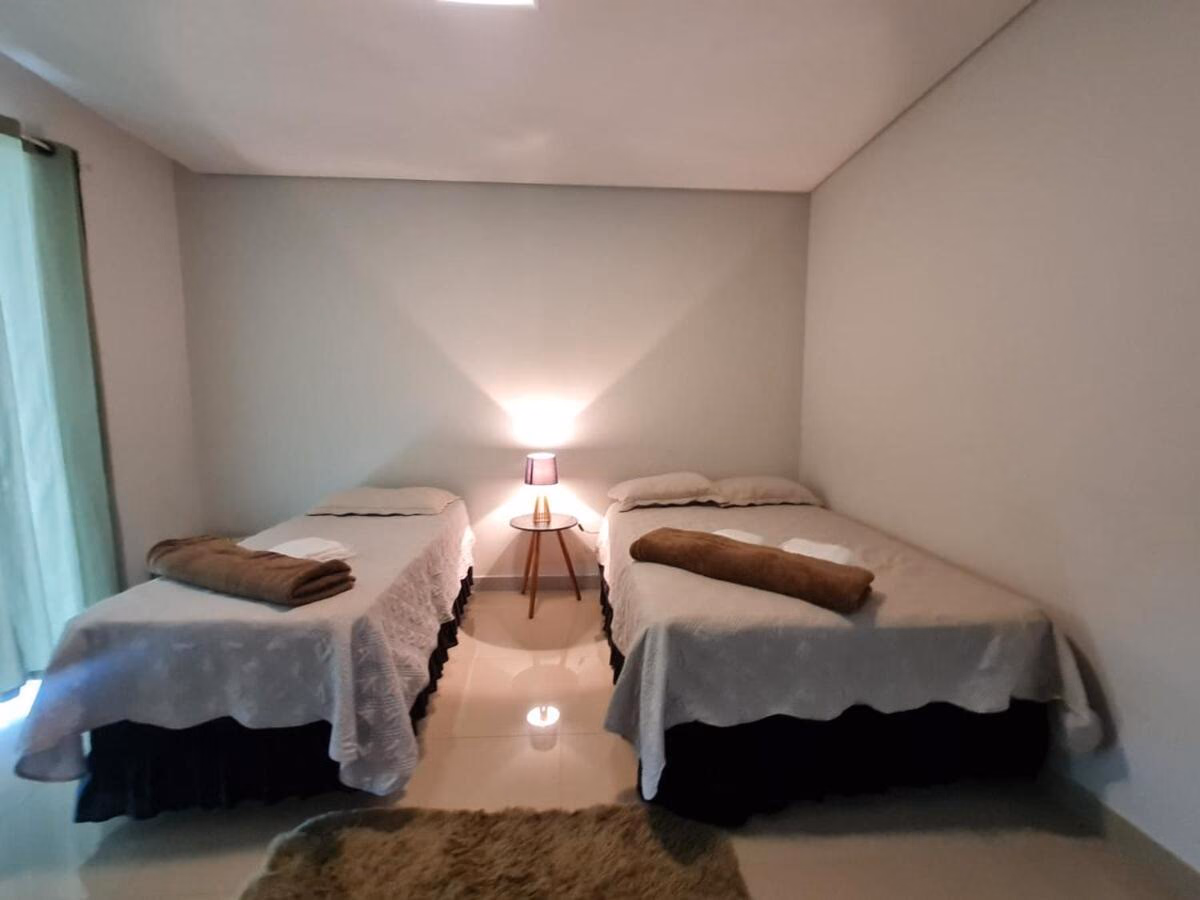 Quarto com duas camas de casal separadas por criado-mudo